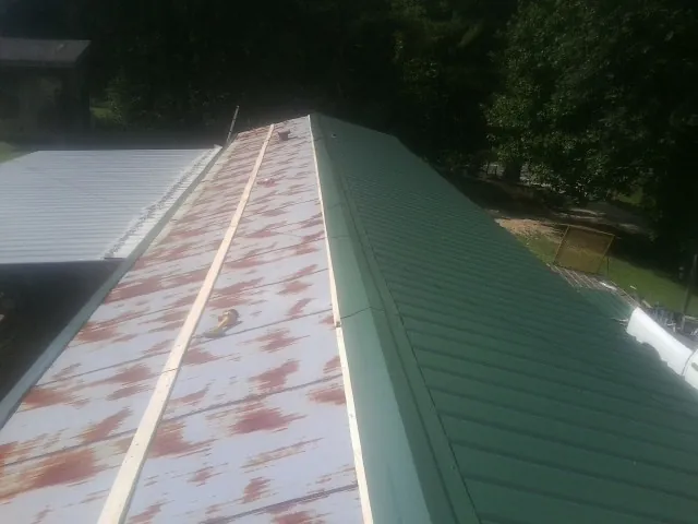 Old rusted panels beside newly installed green metal roofing — Wind Damage Roof Repair by Roofing Brothers in Etowah