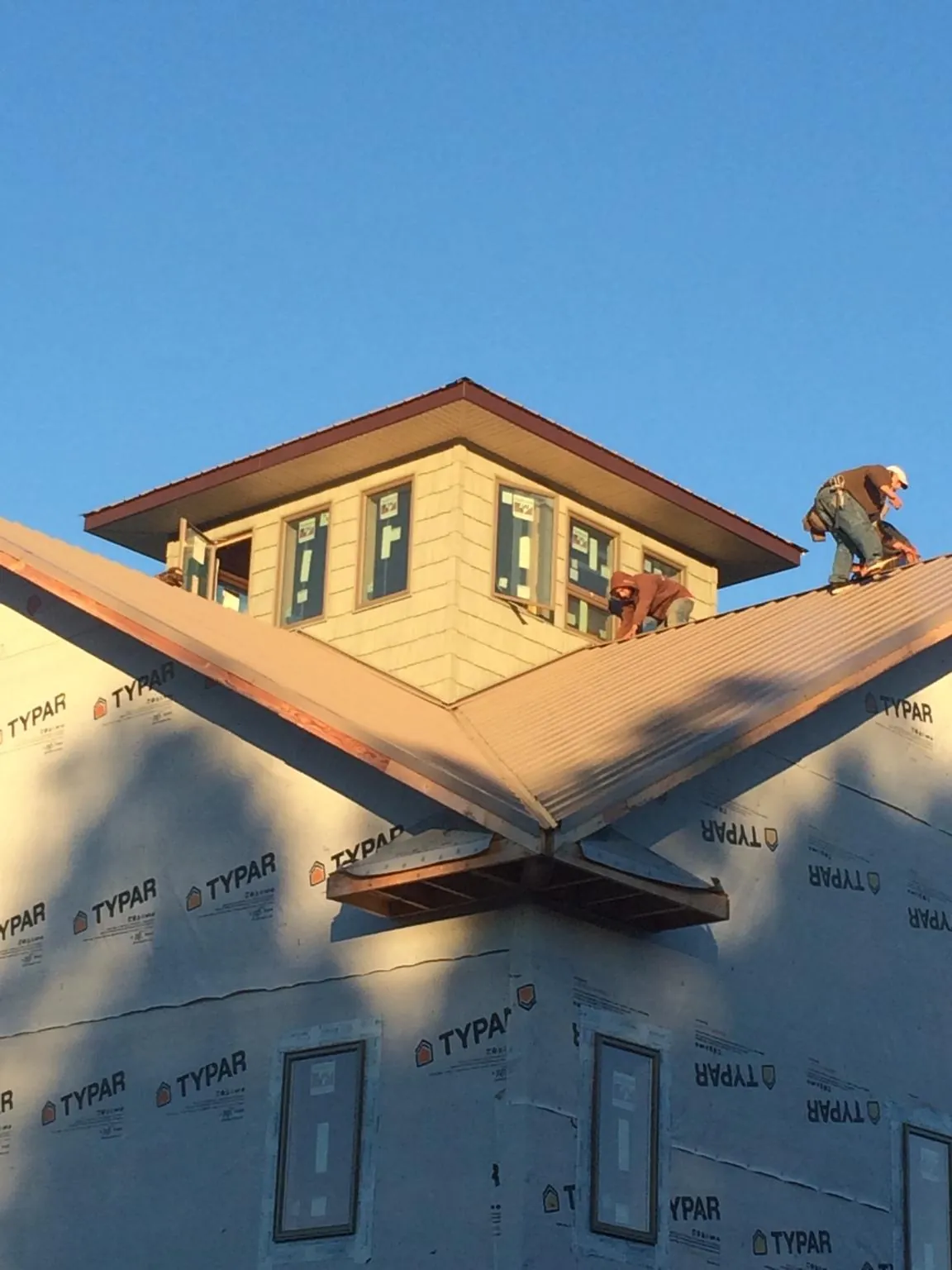 Roofers working around a rooftop cupola on a new metal roof at sunset — Roof Waterproofing in Etowah by Roofing Brothers